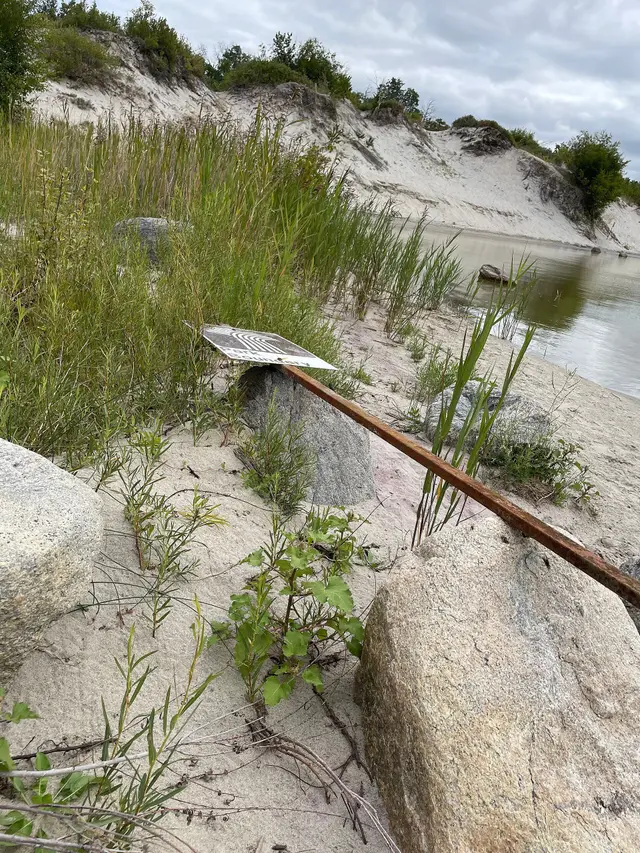 Fallen park boundary sign by the lake and sand dunes